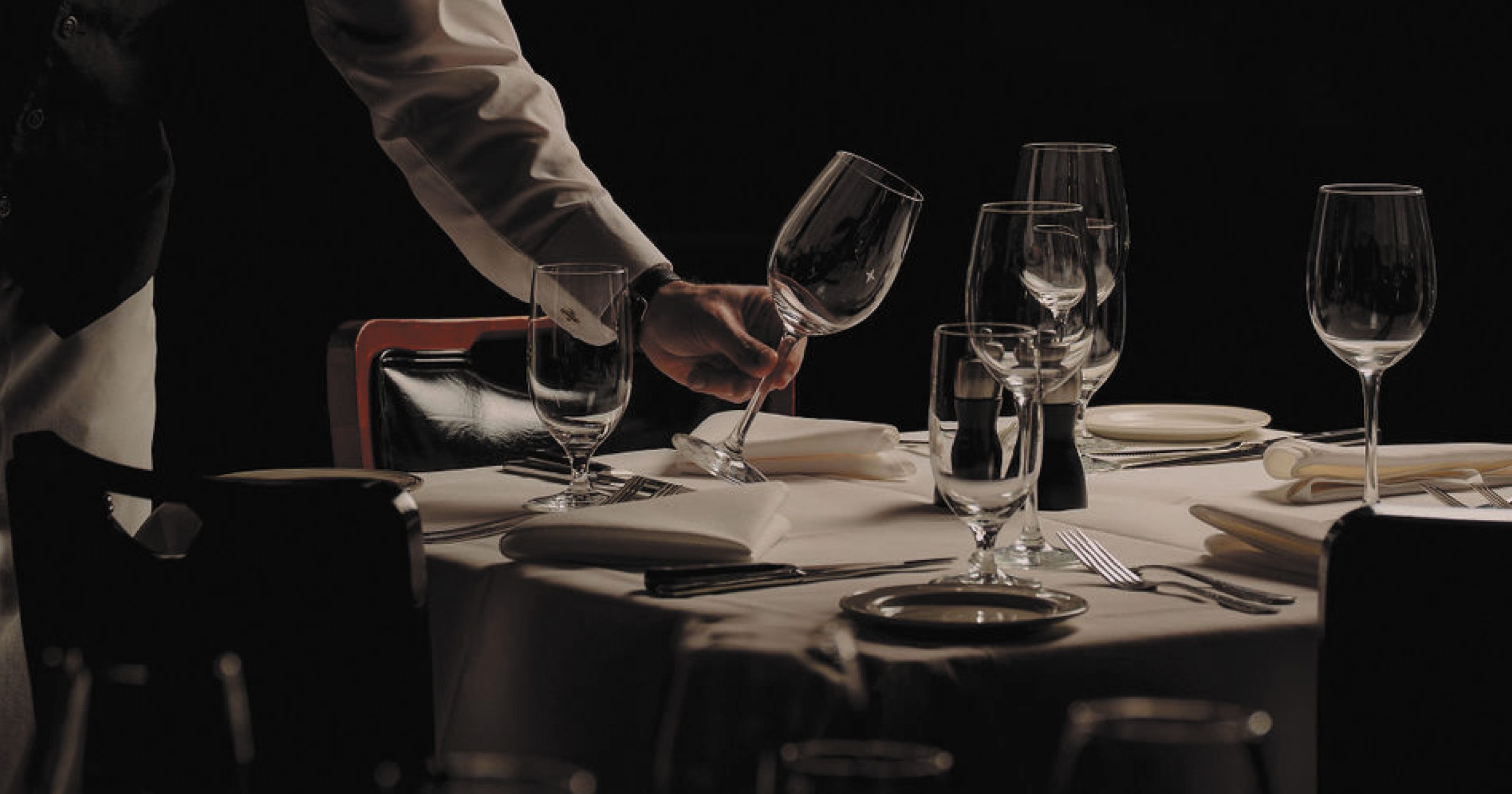 Server setting the table with wine glasses