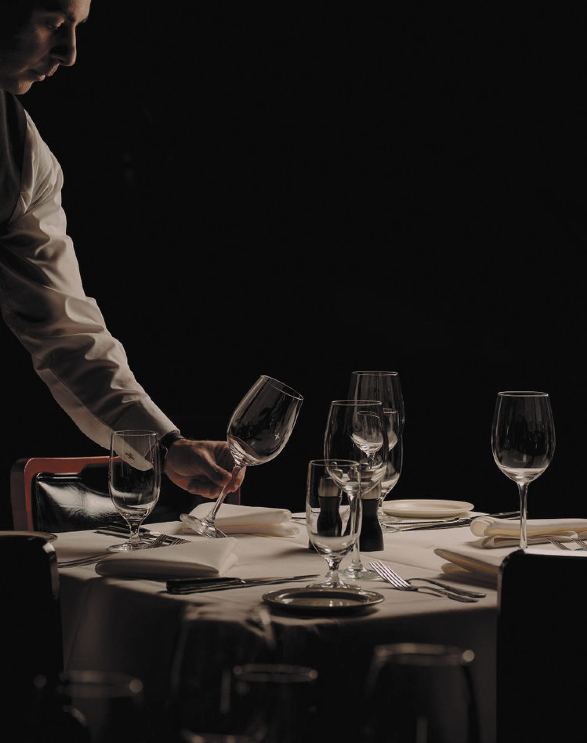 Server setting the table with wine glasses